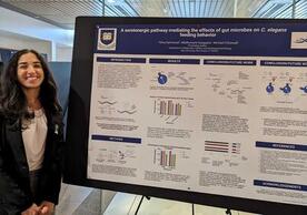 Image shows Dina Garmroudi smiling next to her research poster